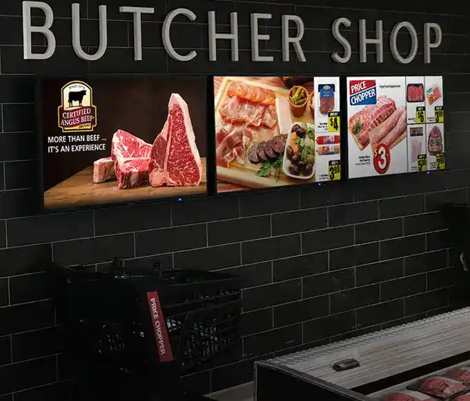 3 tableros de menú digitales montados en la pared de una carnicería