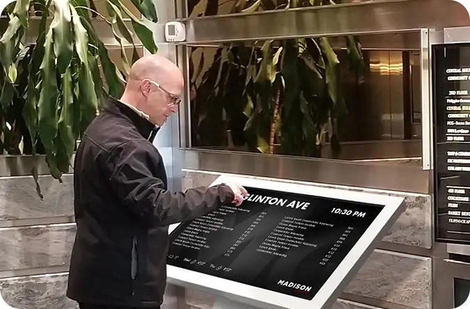 A visitor using a lobby directory kiosk in an office tower
