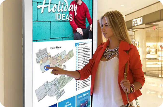 A shopper using a mall directory kiosk beside a retail storefront